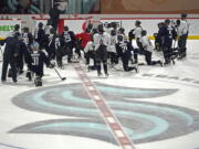 Seattle Kraken players kneel on the ice at their training facility as head coach Dave Hakstol outlines a play during NHL hockey practice, Thursday, Oct. 21, 2021, in Seattle. The Kraken will face the Vancouver Canucks, Saturday in Seattle for the expansion team's home opener. (AP Photo/Ted S.