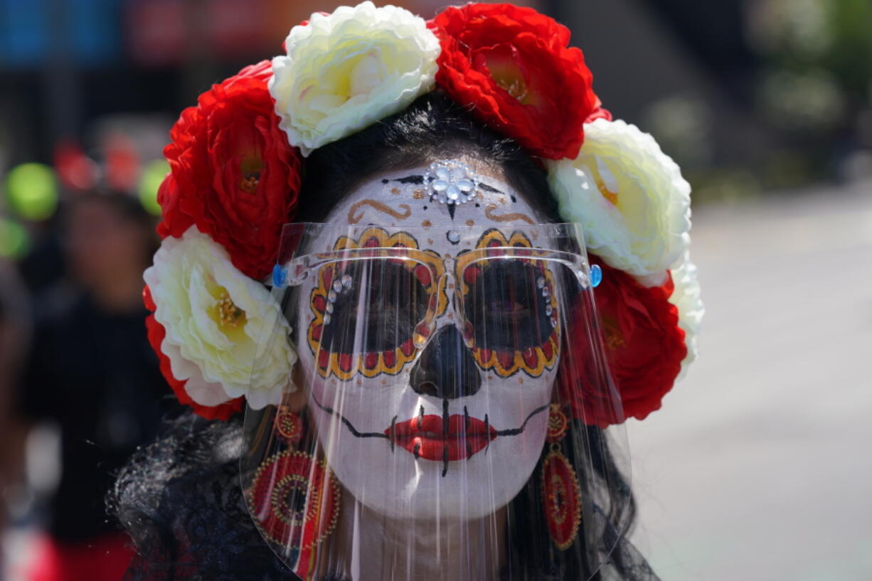 A woman made up as a "Catrina" and wearing a face shield posed for a photo during Day of the Dead festivities in Mexico City, Sunday, Oct. 31, 2021. Altars and artwork from around the country were on display in a parade, as Mexicans honor the Day of the Dead.