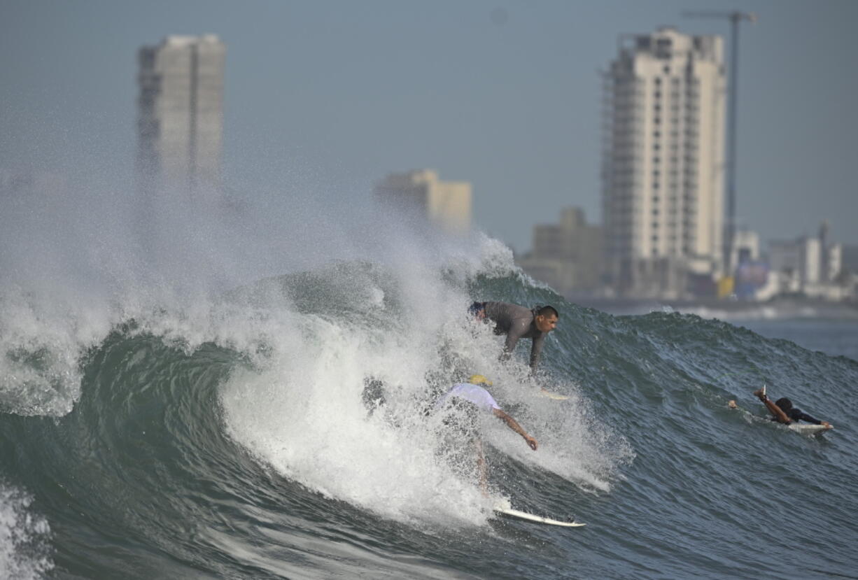 People surf at Pinitos beach prior landfall of tropical storm Pamela, in Mazatlan, Mexico, Tuesday, Oct. 12, 2021. Hurricane Pamela weakened to a tropical storm Tuesday afternoon as it meandered off Mexico's Pacific coast. Forecasters said it was expected to regain strength overnight and be a hurricane when making landfall somewhere near the port of Mazatlan Wednesday.