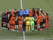 Portland Thorns and Houston Dash players, along with referees, gather at midfield Wednesday, in demonstration of solidarity with two former NWSL players who came forward with allegations of sexual harassment and misconduct against a former coach.