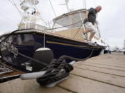 Brad White, of Marshfield, Mass., secures lines for his 33-foot vessel White Cap, at Mill Wharf Marina, Tuesday, Oct. 26, 2021, in Scituate, Mass. Authorities say a powerful autumn storm is bearing down on southern New England, packing potentially damaging winds and threatening to dump as much as six inches of rain in some areas from Tuesday afternoon into Wednesday, Oct. 27. White, a licensed captain, who has been sailing out of Scituate for over 50 years, operates a service called New England Burials At Sea LLC, that provides ash scattering and full body burials at sea.