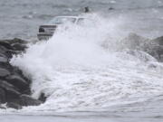 A car making its way across the Gooseberry Island causeway, Tuesday, Oct. 26, 2021, in Westport, Mass., is covered by a large wave, as a nor'easter makes its way across the northeast.