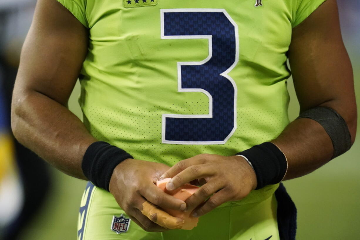 Seattle Seahawks quarterback Russell Wilson holds a sponge near his taped injured finger during the fourth quarter of an NFL football game against the Los Angeles Rams, Thursday, Oct. 7, 2021, in Seattle. Wilson left the game after the injury and the Rams won 26-17.