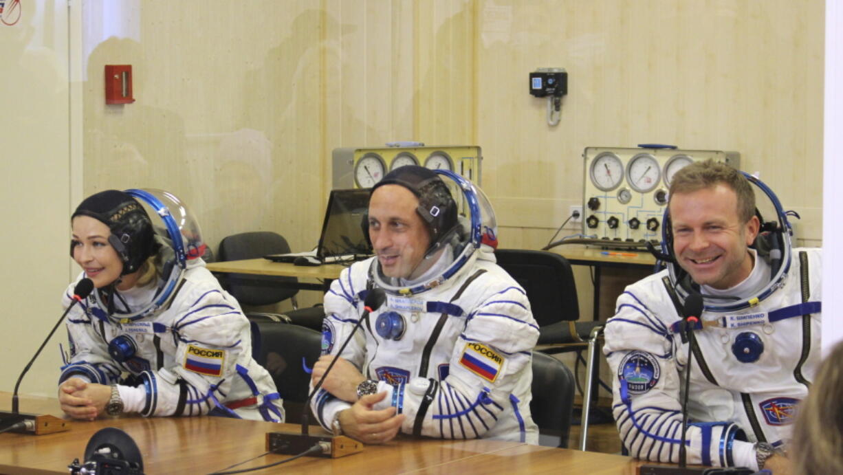 In this handout photo released by Roscosmos, actress Yulia Peresild, left, film director Klim Shipenko, right, and cosmonaut Anton Shkaplerov speak with their relatives through a safety glass prior the launch at the Baikonur Cosmodrome, Kazakhstan, Tuesday, Oct. 5, 2021. Actress Yulia Peresild and film director Klim Shipenko blasted off Tuesday for the International Space Station in a Russian Soyuz spacecraft together with cosmonaut Anton Shkaplerov, a veteran of three space missions, to make a feature film in orbit.