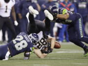 New Orleans Saints' Adam Trautman (82) fumbles between Seattle Seahawks' Ugo Amadi (28) and Bobby Wagner (54) during the second half of an NFL football game, Monday, Oct. 25, 2021, in Seattle. The Seahawks recovered the ball.