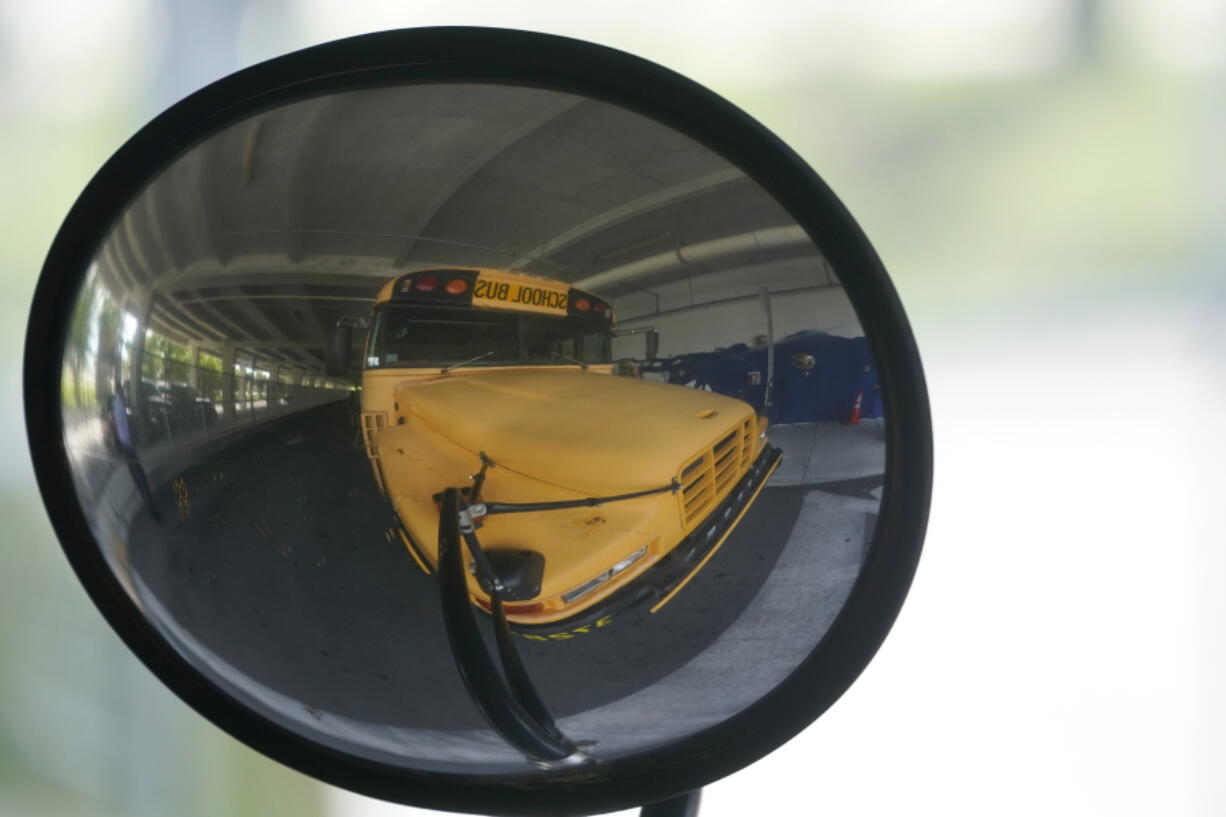 A diesel-powered school bus is reflected in a mirror at MAST Academy, Wednesday, Sept. 29, 2021, in Miami. Student Holly Thorpe, 14, urged the Miami-Dade County Public Schools to considering replacing foul-smelling diesel school buses with electric vehicles. The school board voted this week to use a state grant to purchase up to 50 electric buses. Miami-Dade is joining a growing number of school districts transitioning from diesel to more environmentally-friendly electric school buses.