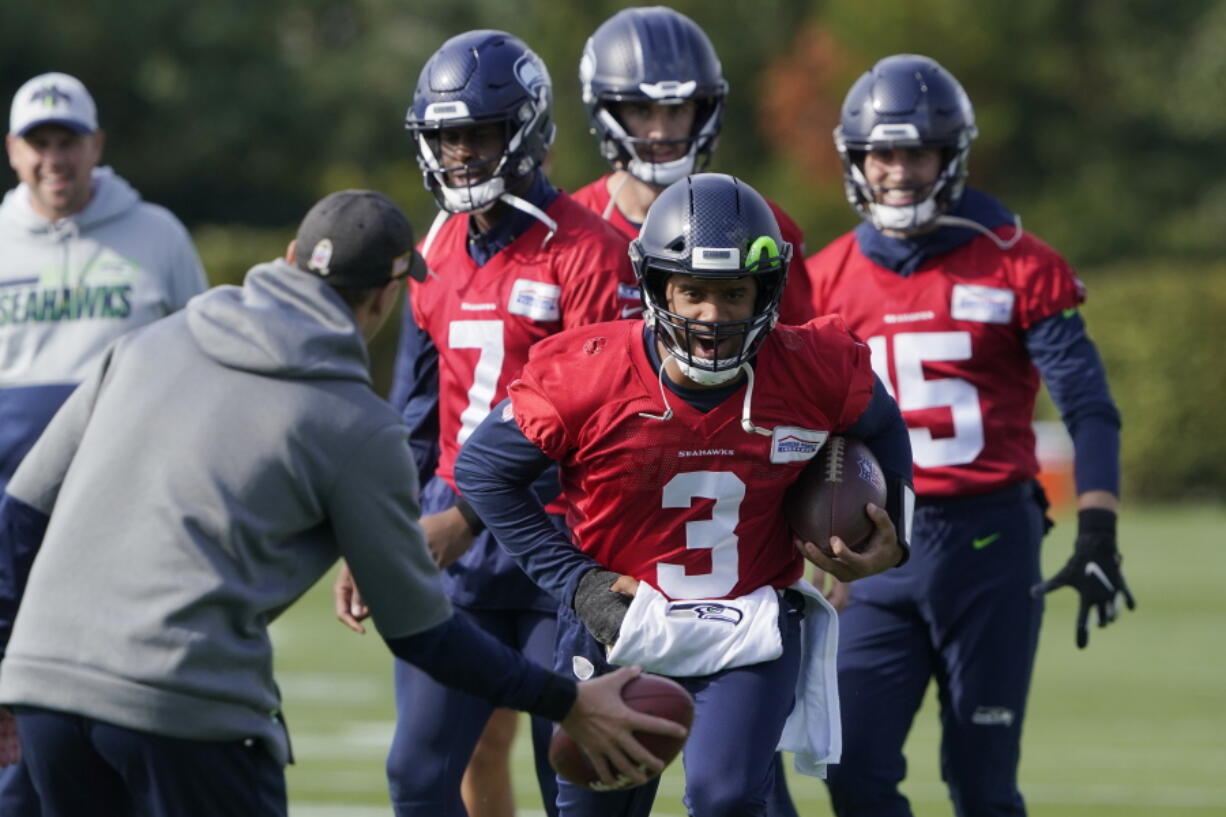 Seattle Seahawks quarterback Russell Wilson (3) keeps his injured hand in a pad as he runs through a warmup drill with backup quarterback Geno Smith (7) behind him during NFL football practice, Wednesday, Oct. 13, 2021, in Renton, Wash. Wilson had surgery on his hand last Friday, and Smith is expected to be the starting quarterback Sunday when the Seahawks play the Pittsburgh Steelers on the road. (AP Photo/Ted S.