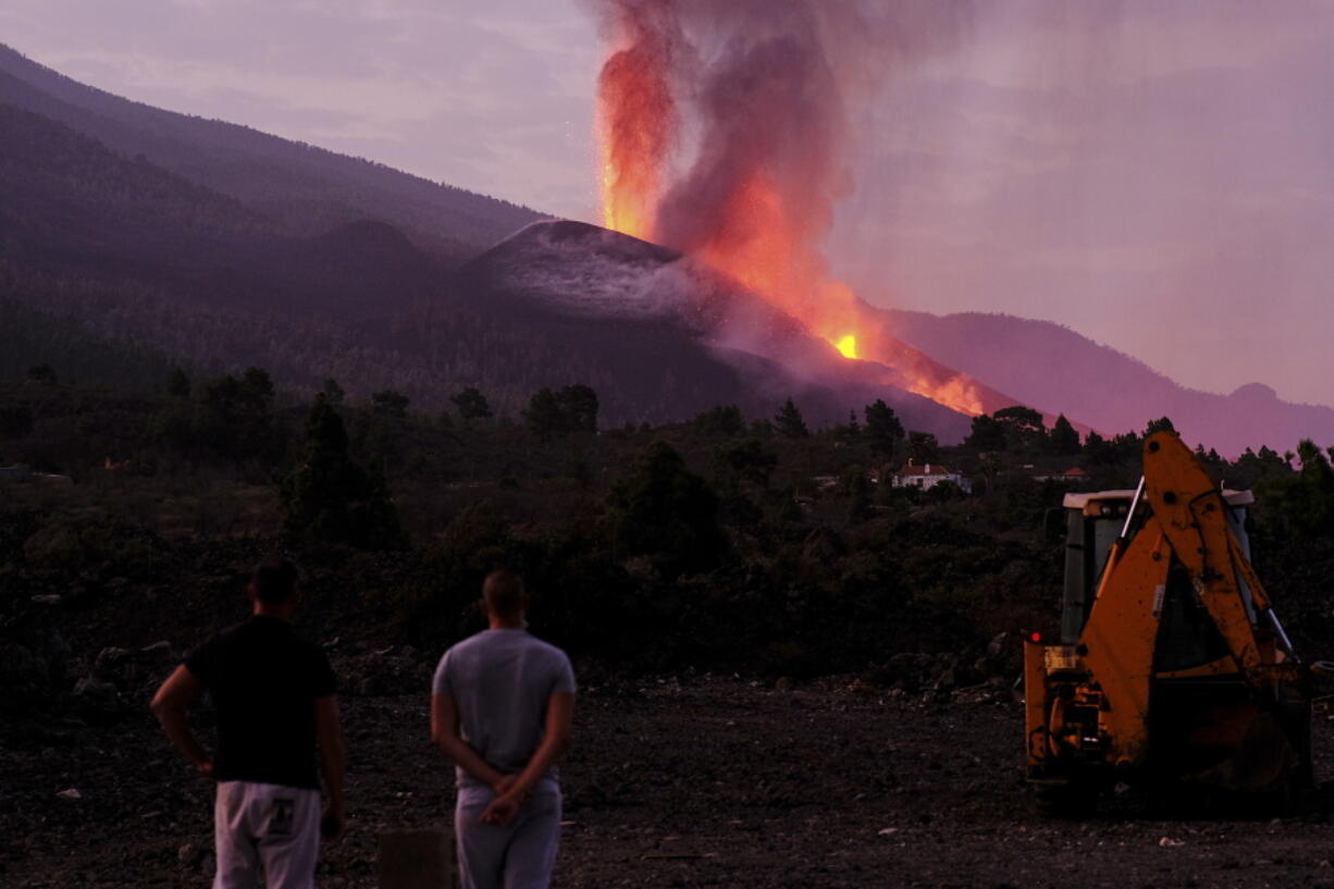 People watch Friday as lava spews from the Cumbre Vieja crater on La Palma, Canary Islands, Spain. The volcano has blown open new fissures on its hillside.