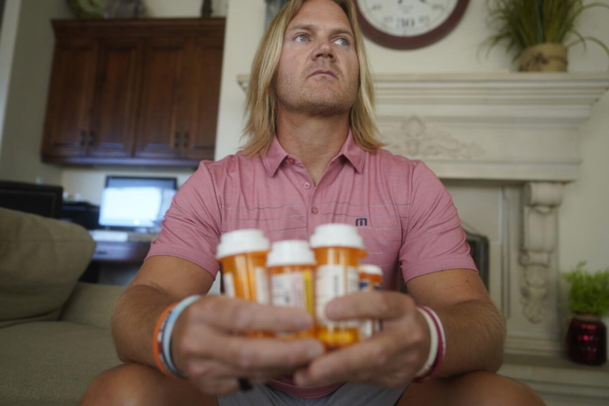 David Stringham holds prescription bottles at his home Monday, Aug. 23, 2021, in Provo, Utah. Stringham says undergoing a procedure for shoulder and elbow pain at a local clinic in 2018 was "the worst decision of my life" and left him in more pain. Since then, a neurologist has told Stringham he probably suffered nerve damage at the places where he was injected.