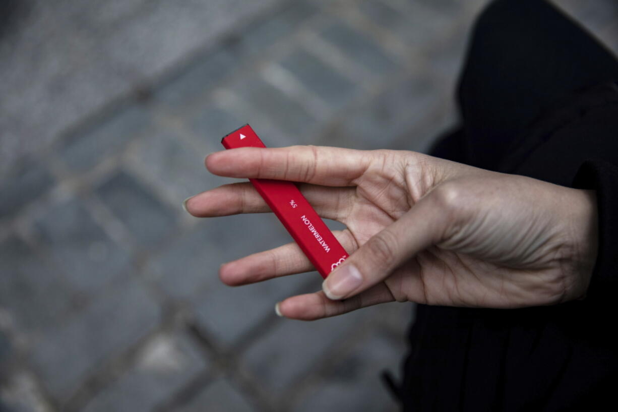 FILE - In this Jan. 31, 2020 file photo a woman holds a Puff Bar flavored disposable vape device in New York.  Government researchers reported a big drop in teen vaping this year as many U.S. students were forced to learn from home due to the COVID-19 pandemic. U.S. health officials urged caution in interpreting the numbers Thursday, Sept.