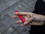 FILE - In this Jan. 31, 2020 file photo a woman holds a Puff Bar flavored disposable vape device in New York.  Government researchers reported a big drop in teen vaping this year as many U.S. students were forced to learn from home due to the COVID-19 pandemic. U.S. health officials urged caution in interpreting the numbers Thursday, Sept.