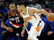 Phoenix Suns guard Devin Booker (1) looks to pass as Portland Portland Trail Blazers forward Norman Powell (24) defends during the first half of a preseason NBA basketball game, Wednesday, Oct. 13, 2021, in Phoenix.