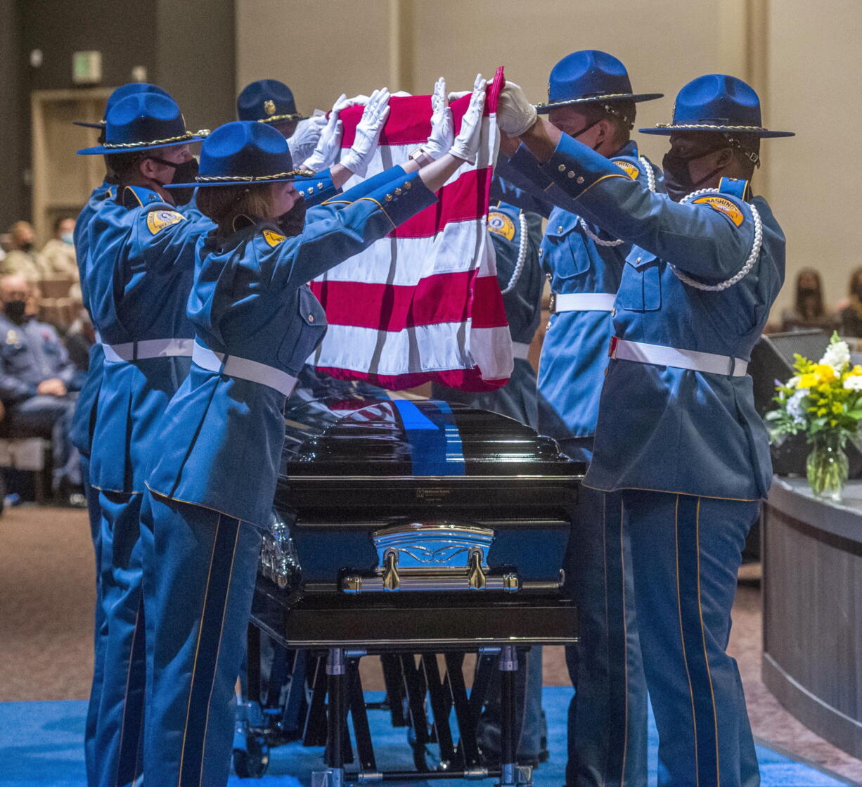 Members of the honor guard for the Washington State Patrol carefully remove an American flag covering the casket bearing trooper Eric Gunderson during a memorial service, Monday, Oct. 4, 2021, at Church For All Nations in Tacoma, Wash. Gunderson, recently died from COVID-19, which the agency said he contracted while on duty. The flag was presented to Gunderson's wife, Kameron.