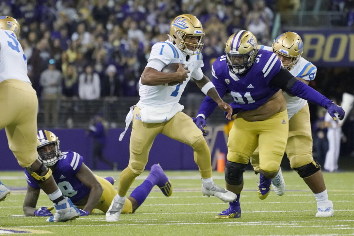 UCLA quarterback Dorian Thompson-Robinson (1) keeps the ball as Washington defensive lineman Tuli Letuligasenoa (91) pursues during the first half of an NCAA college football game Saturday, Oct. 16, 2021, in Seattle. (AP Photo/Ted S.