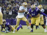 UCLA quarterback Dorian Thompson-Robinson (1) keeps the ball as Washington defensive lineman Tuli Letuligasenoa (91) pursues during the first half of an NCAA college football game Saturday, Oct. 16, 2021, in Seattle. (AP Photo/Ted S.