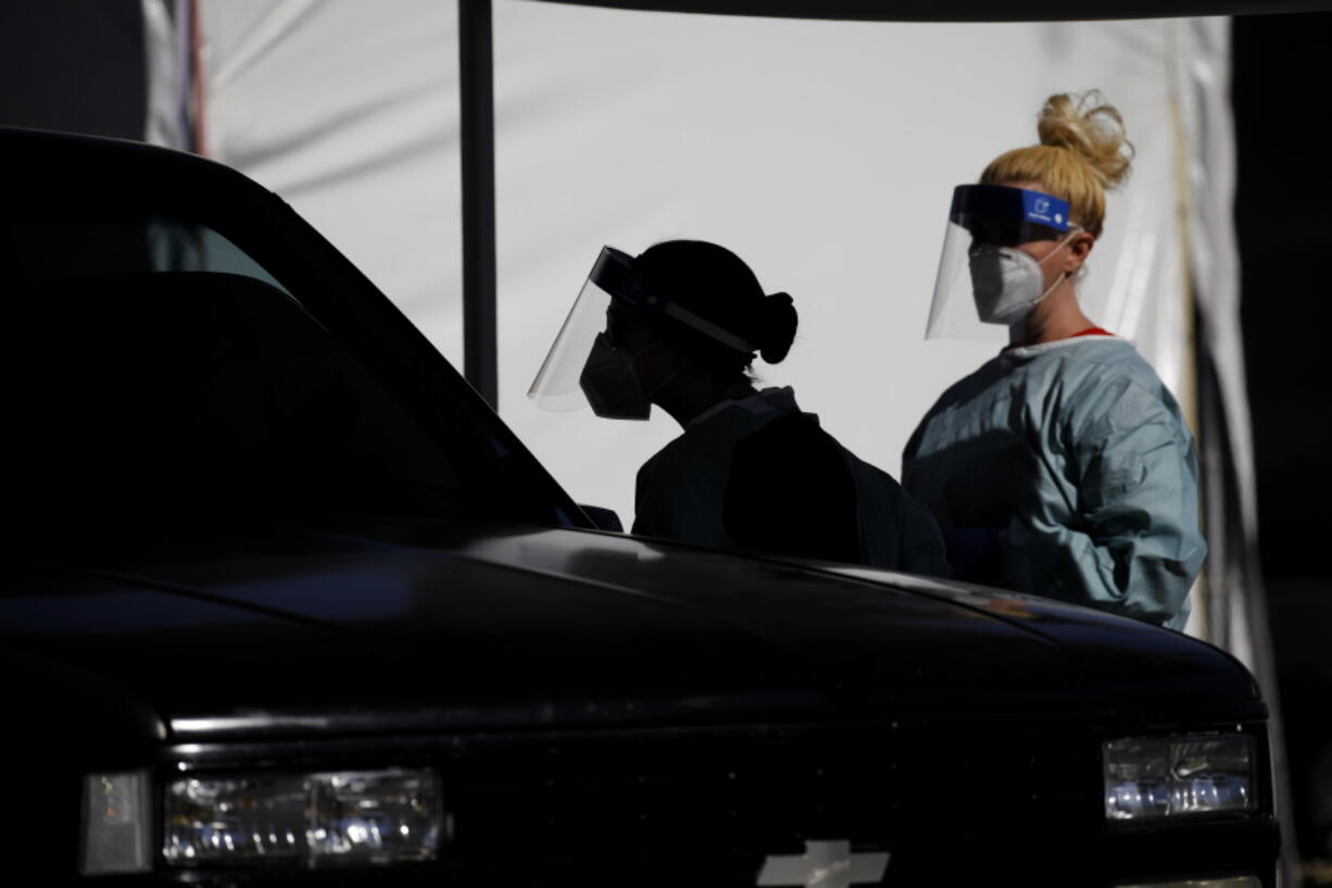 FILE - In this July 10, 2020, file photo, healthcare workers test patients in their cars at a drive-thru coronavirus testing site run by the University of Nevada Las Vegas School of Medicine and the Nevada National Guard in Las Vegas. Nevada this week became one of the last states to include rapid antigen tests in its coronavirus tallies. Experts say the change could provide a fuller picture of the pandemic but also upend metrics used to gauge how the virus is spreading.