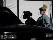 FILE - In this July 10, 2020, file photo, healthcare workers test patients in their cars at a drive-thru coronavirus testing site run by the University of Nevada Las Vegas School of Medicine and the Nevada National Guard in Las Vegas. Nevada this week became one of the last states to include rapid antigen tests in its coronavirus tallies. Experts say the change could provide a fuller picture of the pandemic but also upend metrics used to gauge how the virus is spreading.