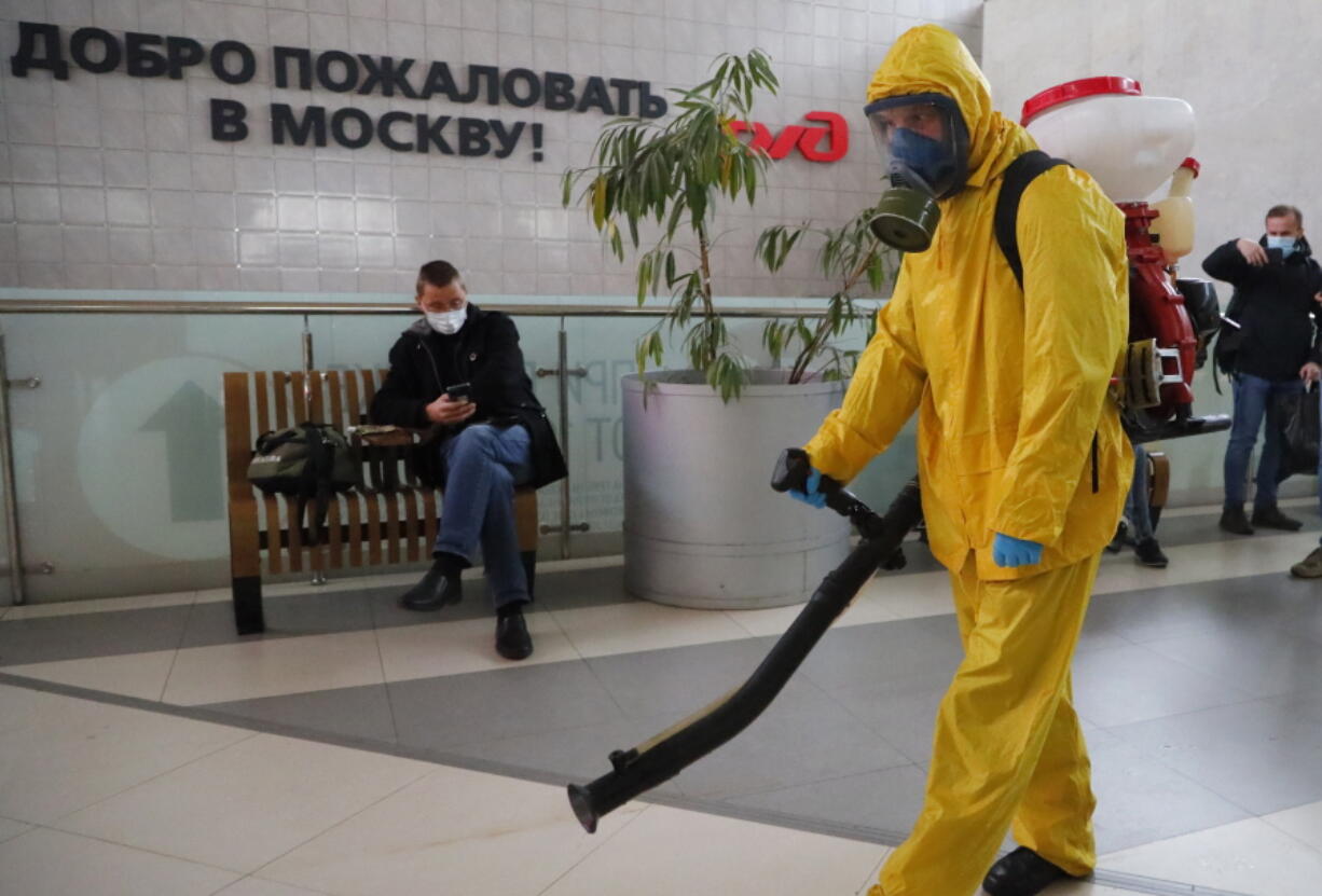 An employee of the Federal State Center for Special Risk Rescue Operations of Russia Emergency Situations disinfects Leningradsky railway station in Moscow, Russia, Tuesday, Oct. 19, 2021, with the sign reading "Welcome to Moscow" on the wall. Russia registered another daily record of coronavirus deaths Tuesday as rapidly surging contagion raised pressure on the country's health care system. The daily coronavirus mortality numbers have been surging for weeks and topped 1,000 for the first time over the weekend amid sluggish vaccination rates and the government's reluctance to toughen restrictions.