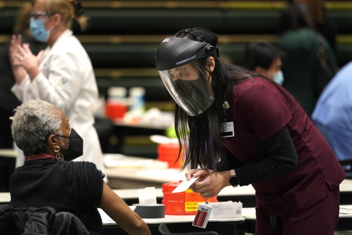 FILE - In this Jan. 24, 2021, file photo, Jenny Park, right, a clinical pharmacist with Virginia Mason Franciscan Health, explains the two-shot dosing of the Pfizer COVID-19 vaccine during a one-day vaccination clinic set up in an Amazon.com facility in Seattle. Monday, Oct. 18, 2021, was the final day for thousands of workers in Washington to prove they've been fully vaccinated for COVID-19 in order to keep their jobs. (AP Photo/Ted S.