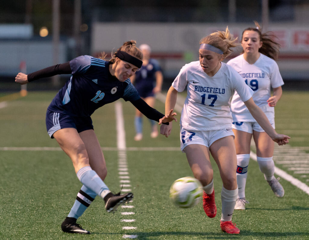 Hockinson's Ellie Ritter delivers a cross as Ridgefield's Ava Kruckenberg defends in the 2A District Girls Soccer Championship on Thursday, Nov. 4, 2021, at District Stadium in Battle Ground.