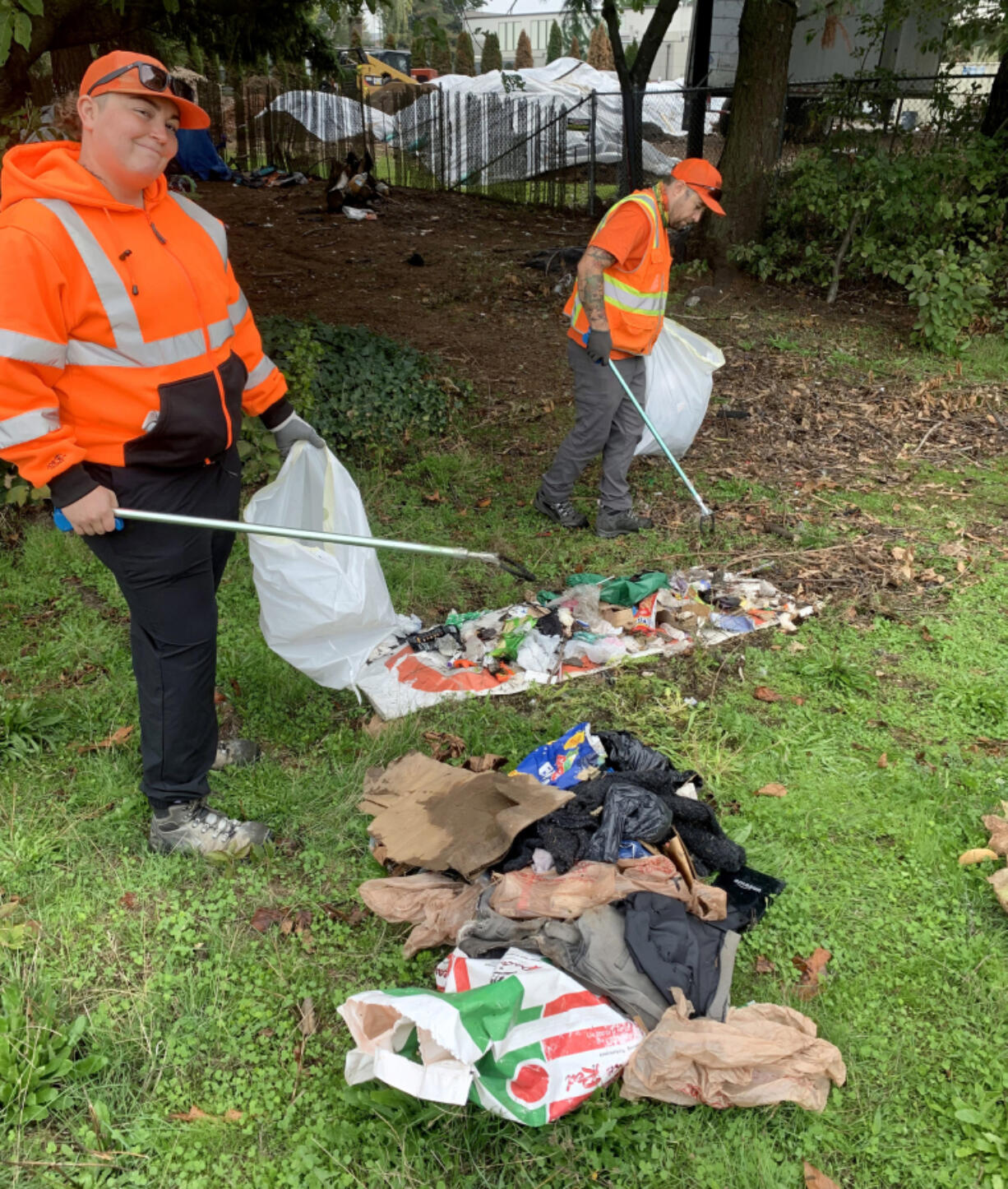 Crew members Ashley Brown, left, and Jerome Warren clean up litter from the roadway.