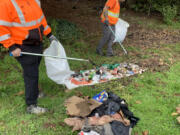 Crew members Ashley Brown, left, and Jerome Warren clean up litter from the roadway.