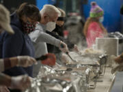 Volunteer Vern Toedtli of Vancouver, at center, stirs the bean and corn station at the turkey dinner assembly line Thursday at the Clark County Event Center at the Fairgrounds. About 1,600 turkey dinners were prepared and delivered by Clark County volunteers to the needy this Thanksgiving.