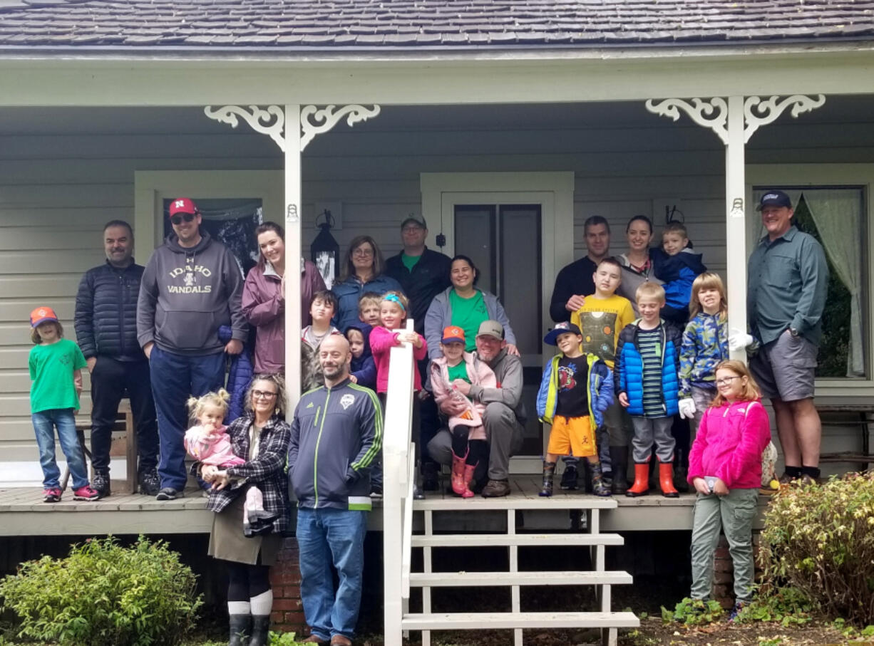 EVERGREEN HIGHWAY: Tiger Den Cub Scouts from Pack 310, under the leadership of Margarita Skeels, earned badges planting mums and pansies at the Jane Weber Evergreen Arboretum. Here are the scouts and their families on the porch of the historic Stanger House on the grounds of the arboretum.