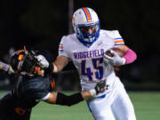 Ridgefield's Connor Delamarter stiff arms a Washougal defender in a 2A Greater St. Helens League football game on Friday, Oct. 1, 2021, at Fishback Stadium in Washougal.