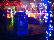 A Lincoln neighborhood house is illuminated with holiday lights while the TARDIS library stands sentinel in 2019.