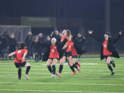 Camas girls soccer team members Jasmine Whittington (6), Anna Mooney and Lily Loughney (16) charge in celebration toward Nora Melcher (8) after Melcher converted the winning goal in the penalty-kick shootout in the Papermakers? win over Issaquah for the 4A state championship in Puyallup on Nov. 20, 2021.
