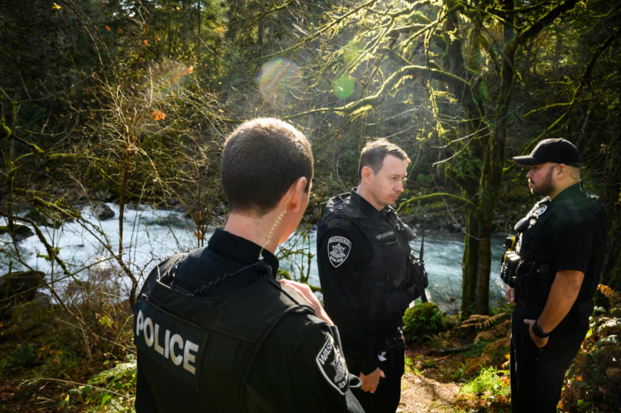 Washougal police Officers Trevor Claudson, from left, Francis Reagan and Ryan Castro stand Monday on the bank of the Washougal River where they rescued a woman from drowning in 2019. Reagan, who swam through the cold water to hold the woman's head above water for about 45 minutes, was awarded the Washington State Law Enforcement Medal of Honor for the rescue. (Molly J.