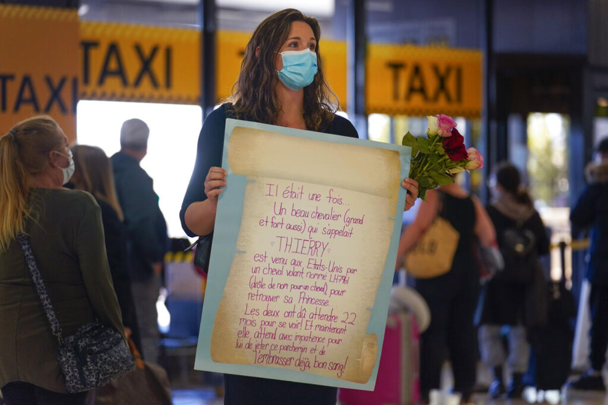 MaKensi Kastl waits with flowers and sign for her boyfriend, who is arriving from France, at Newark Liberty International Airport in Newark, N.J., Monday, Nov. 8, 2021. The couple has not seen one another in person for over a year due to pandemic travel restrictions. The U.S. lifted restrictions Monday on travel from a long list of countries including Mexico, Canada and most of Europe, setting the stage for emotional reunions nearly two years in the making and providing a boost for the airline and tourism industries decimated by the pandemic.