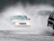 A westbound car is caught in a spray of water thrown up by a pickup truck on Highway 20 Monday, Nov. 15, 2021, near Hamilton, Wash. The heavy rainfall of recent days will brought major flooding of the Skagit River that is expected to continue into at least Monday evening.