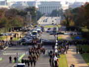 Troops march during a full honors procession honoring the centennial anniversary of the Tomb of the Unknown Soldier, Thursday, Nov. 11, 2021 at Arlington National Cemetery in Arlington, Va. The Lincoln Memorial in Washington is shown in the distance.