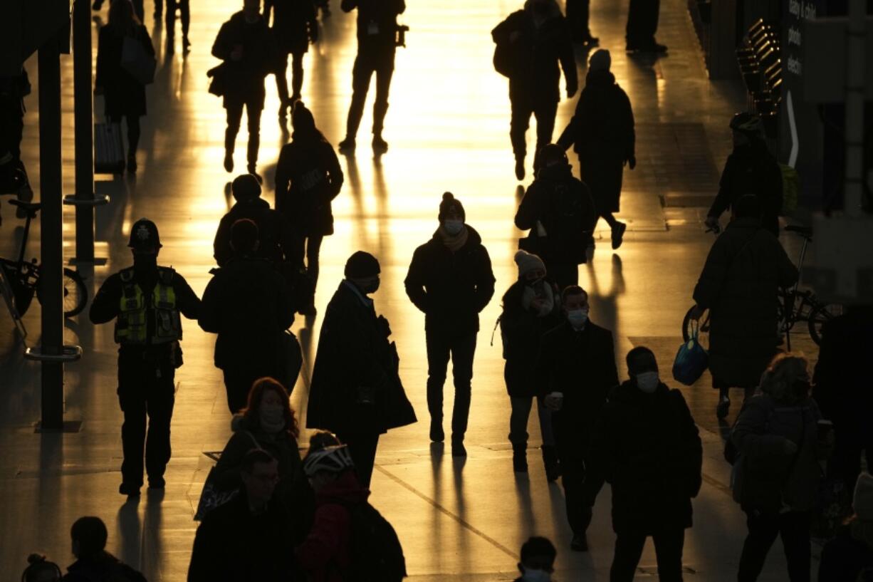 People pass through Waterloo train station, in London, during the morning rush hour, Monday, Nov. 29, 2021. The new potentially more contagious omicron variant of the coronavirus popped up in more European countries on Saturday, just days after being identified in South Africa, leaving governments around the world scrambling to stop the spread. In Britain, Prime Minister Boris Johnson said mask-wearing in shops and on public transport will be required, starting Tuesday.