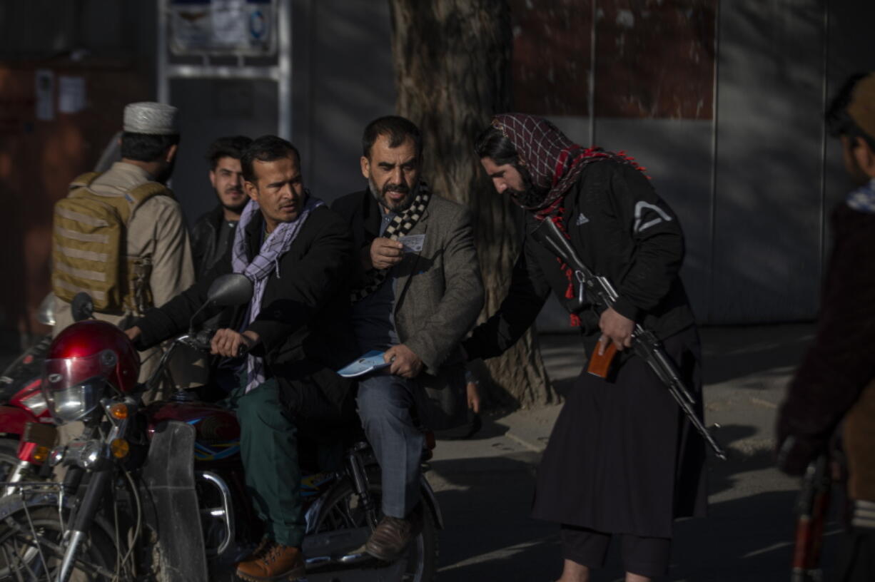 Taliban fighter checks documents after an explosion Tuesday, Nov. 2, 2021.