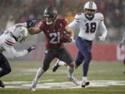 Washington State running back Max Borghi (21) fends off a tackle from Arizona free safety Jaydin Young, left, as he runs for a touchdown and Arizona linebacker Kenny Hebert (18) closes in during the first half of an NCAA college football game, Friday, Nov. 19, 2021, in Pullman, Wash. (AP Photo/Ted S.