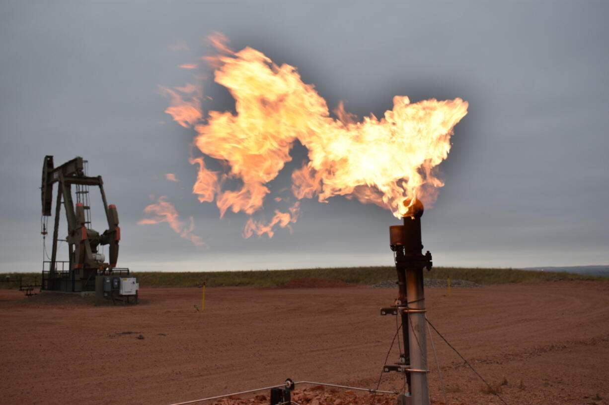 FILE - A flare burns natural gas at an oil well on Aug. 26, 2021, in Watford City, N.D. A new federal report released Friday, Oct. 29, 2021, says fossil fuel extraction from federal lands produced more than 1 billion tons (918 million metric tons) of greenhouse gases last year.