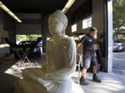 Dave Ley, co-owner of Exoticars, an auto restoration shop specializing in classic vehicles, pulls a restored statue of the Buddha outside Oct. 11 in McCandless, Pa. Workers repaired and repainted the figure for the Pittsburgh Buddhist Center.