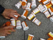 FILE - A protester gathers containers that look like OxyContin bottles at an anti-opioid demonstration in front of the U.S. Department of Health and Human Services headquarters in Washington on April 5, 2019. A California judge has ruled for top drug manufacturers as local governments seek billions of dollars to cover their costs from the nation's opioid epidemic. Orange County Superior Court Judge Peter Wilson issued a tentative ruling Monday, Nov. 1, 2021, that said the governments hadn't proven the pharmaceutical companies used deceptive marketing to increase unnecessary opioid prescriptions and create a public nuisance.