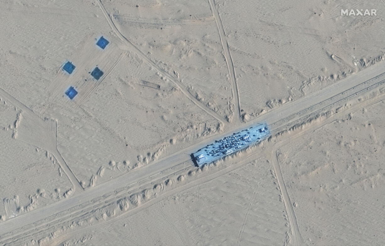 This satellite image provided by Maxar Technologies shows a building on rail tracks in Ruoqiang county, China, Wednesday, Oct. 20, 2021. Satellite images appear to show China has built mock-ups of U.S. Navy aircraft carriers and destroyers in its northwestern desert, such as one at center in this image, possibly as practice for a future naval clash as tensions rise between the nations.