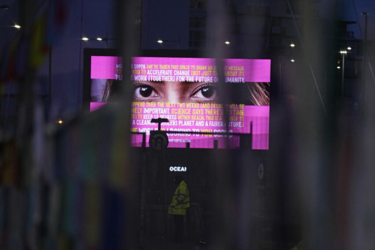 Part of an advertisement can be seen through the fence near the venue for the COP26 U.N. Climate Summit in Glasgow, Scotland, Thursday, Nov. 11, 2021.