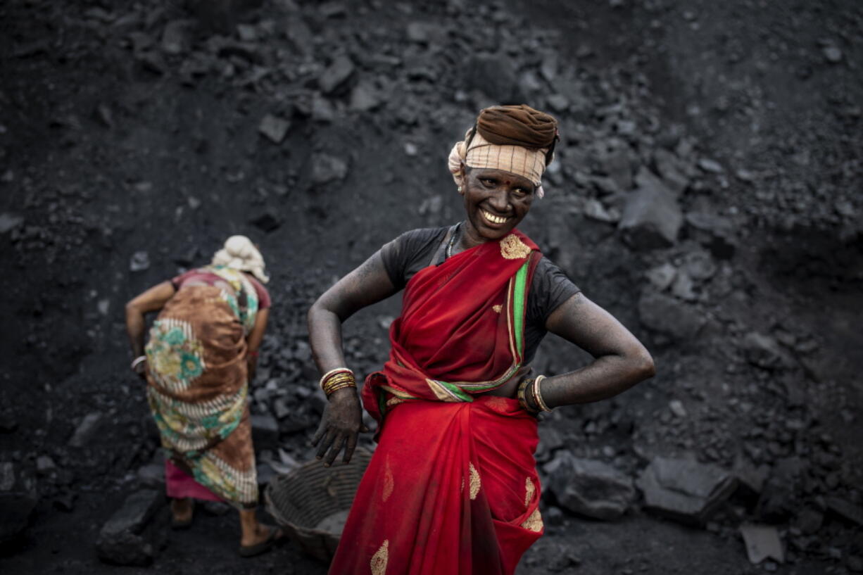 An Indian laborer smiles as she takes a break from loading coal into a truck in Dhanbad, an eastern Indian city in Jharkhand state, Friday, Sept. 24, 2021. A 2021 Indian government study found that Jharkhand state -- among the poorest in India and the state with the nation's largest coal reserves -- is also the most vulnerable Indian state to climate change. Efforts to fight climate change are being held back in part because coal, the biggest single source of climate-changing gases, provides cheap electricity and supports millions of jobs. It's one of the dilemmas facing world leaders gathered in Glasgow, Scotland this week in an attempt to stave off the worst effects of climate change.