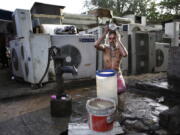 FILE - A migrant daily wage worker bathes at a public well pump on a hot morning in New Delhi, India, Tuesday, May 17, 2016. Scorching summer temperatures, hovering well over 40 degrees Celcius, (104 Fahrenheit) are making life extremely tough for millions of poor across north India. Without access to air conditioning and sometimes even an electric fan, they struggle to cope with the heat in their inadequate homes.