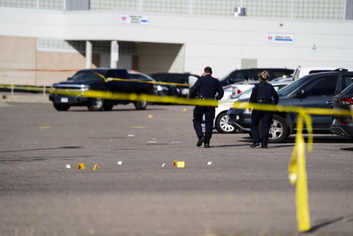 Evidence markers dot the parking lot of Hinkley High School in Aurora, Colo., on Friday, Nov. 19, 2021. Three people were shot Friday in the parking lot of the school, police said. (Philip B.