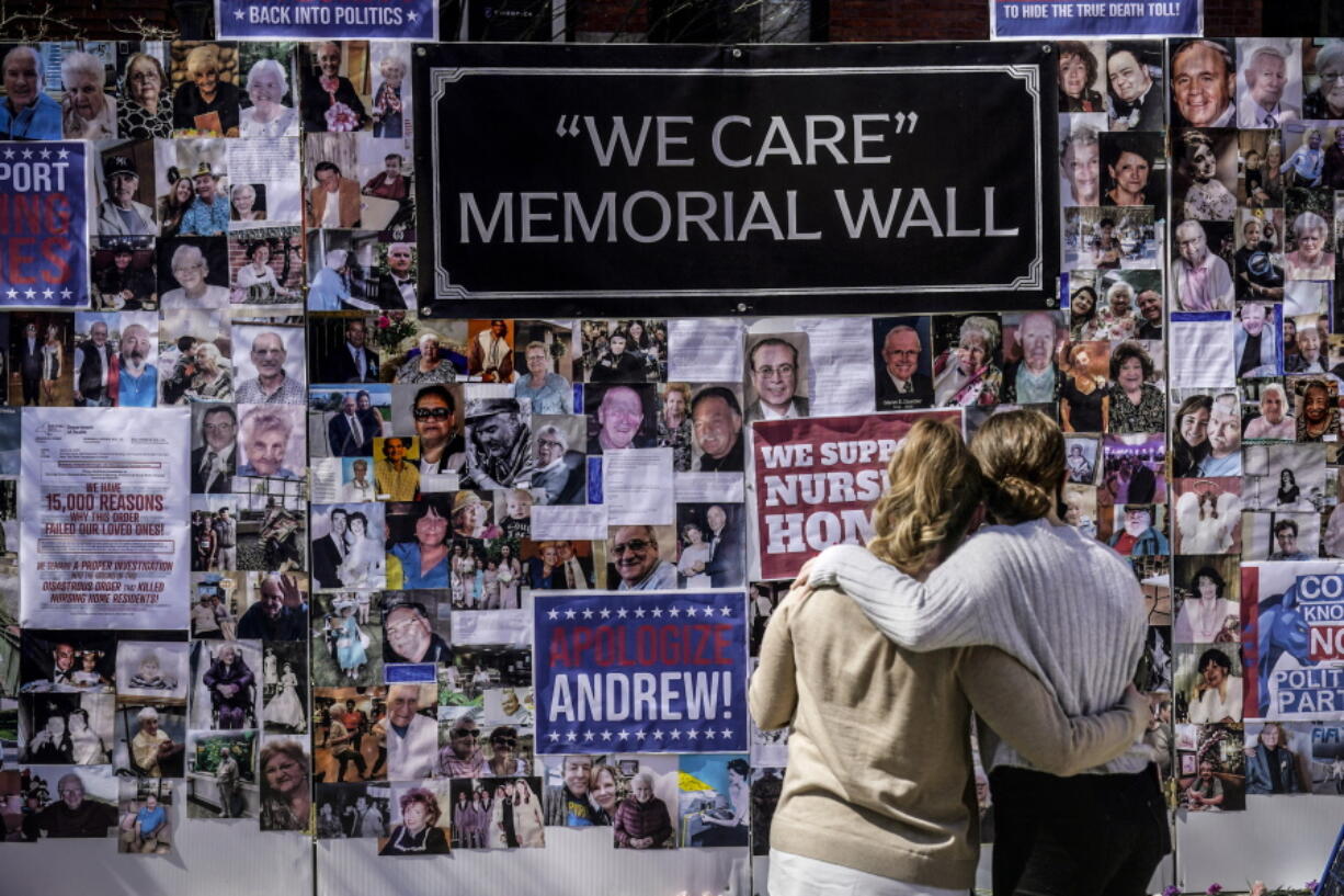 FILE - In this file photo, Theresa Sari, left, and her daughter Leila Ali look at a protest-memorial wall for nursing home residents who died from COVID-19, including Sari's mother Maria Sachse, March 21, 2021, in New York. A state Assembly committee investigation found former New York Gov. Andrew Cuomo's administration made a political decision to misrepresent how many nursing home residents died of COVID-19.