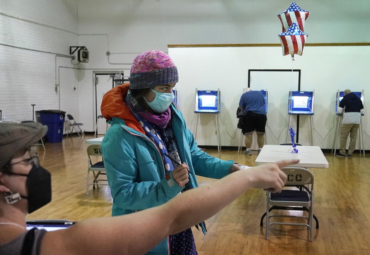 Monica Rojas gets directions from a poll worker on her way to casting her ballot at Sabathani Community Center during municipal elections Tuesday, Nov. 2, 2021, in Minneapolis.  Voters in Minneapolis are deciding whether to replace the city's police department with a new Department of Public Safety.