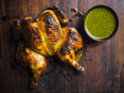 This image released by Milk Street shows a recipe for chutney-glazed spatchcocked chicken. Spatchcocking, or butterflying, involves cutting out a bird's backbone so it can be flattened. This allows the chicken to brown evenly and helps the glaze stay put. Their simple glaze mixes tangy-sweet chutney with butter and turmeric. Citrus juice added to a portion of the glaze before cooking makes a bright dipping sauce.