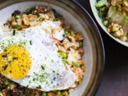 This image released by Milk Street shows a recipe for kimchi and bacon-fried rice, topped with a fried egg and sprinkled with furikake.